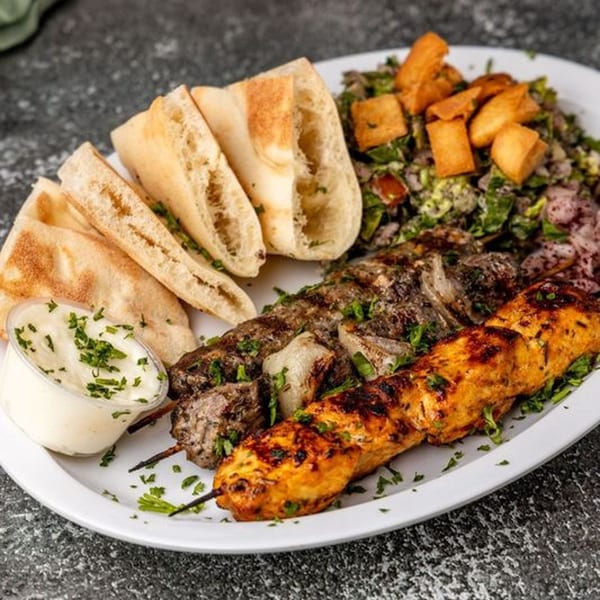 Pita Shop's Mediterranean platter with grilled chicken and beef skewers, pita bread, salad, and sauce.