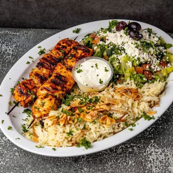 Pita Shop's chicken shish tawook with rice, salad, and a side of white sauce.