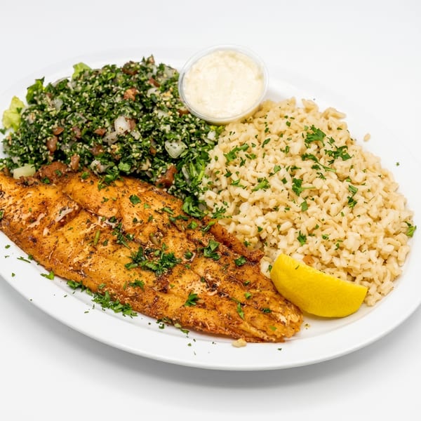 Platter with seasoned fish, brown rice, tabbouleh salad, lemon wedge, and a side of sauce.